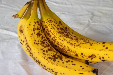 Beyaz kırışık masa örtüsü üzerinde koyu benekli olgun bir muz.