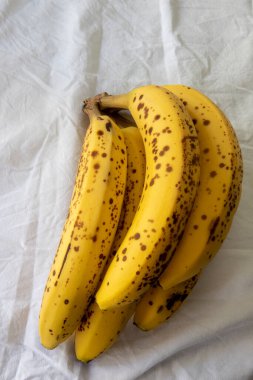 Beyaz kırışık masa örtüsü üzerinde koyu benekli olgun bir muz.