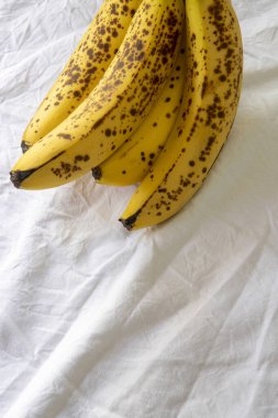 Beyaz kırışık masa örtüsü üzerinde koyu benekli olgun bir muz.