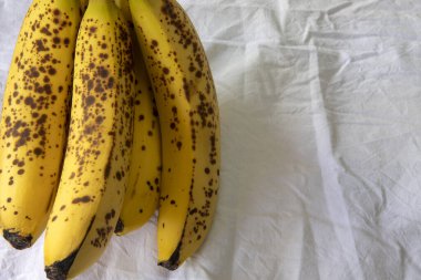 Beyaz kırışık masa örtüsü üzerinde koyu benekli olgun bir muz.