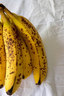 Beyaz kırışık masa örtüsü üzerinde koyu benekli olgun bir muz.