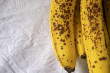 Beyaz kırışık masa örtüsü üzerinde koyu benekli olgun bir muz.