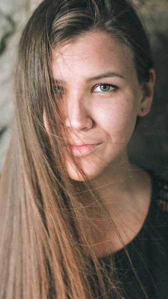 Retrato de close-up de uma menina bonita com cabelos longos que cobrem um olho. Uma jovem mulher olha diretamente para a câmera . — Fotografia de Stock