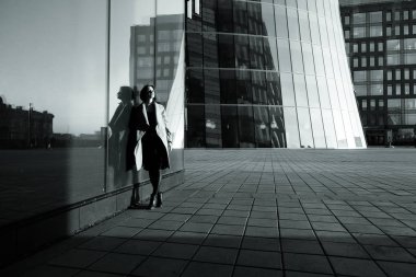 İş merkezine karşı binada yansıtan bir ceket bir kız siyah ve beyaz fotoğraf