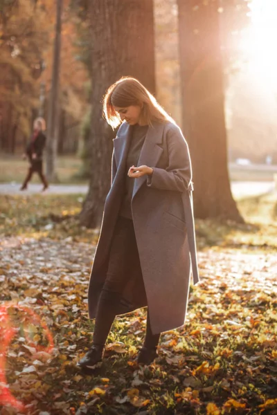 Pretty girl walking in autumn park. Beautiful autumn sunny weather. Young woman enjoying fall. Women fashion. Autumn holidays. People, autumn and lifestyle concept.