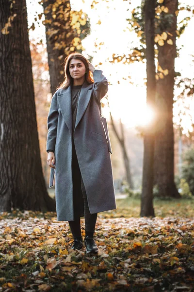 Pretty girl walking in autumn park. Beautiful autumn sunny weather. Young woman enjoying fall. Women fashion. Autumn holidays. People, autumn and lifestyle concept.