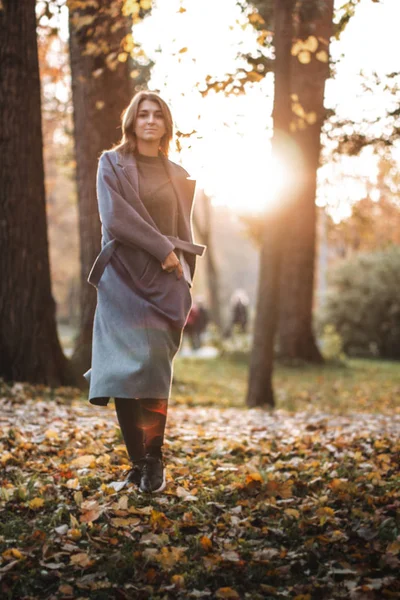 Pretty girl walking in autumn park. Beautiful autumn sunny weather. Young woman enjoying fall. Women fashion. Autumn holidays. People, autumn and lifestyle concept.