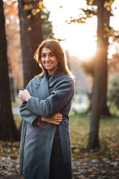 Pretty girl walking in autumn park. Beautiful autumn sunny weather. Young woman enjoying fall. Women fashion. Autumn holidays. People, autumn and lifestyle concept.