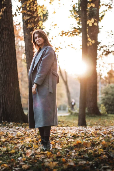 Pretty girl walking in autumn park. Beautiful autumn sunny weather. Young woman enjoying fall. Women fashion. Autumn holidays. People, autumn and lifestyle concept.