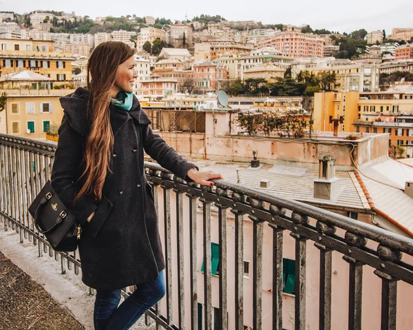 Девушка с длинными волосами в пальто смотрит на панораму Генуи, Италия — стоковое фото