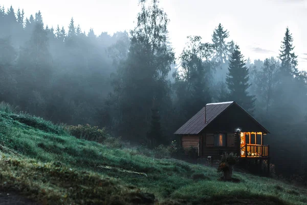 안개가 자욱 한 숲 속의 작은 오래 된 나무 집입니다. 산 풍경. 자연의 개념적 이미지. — 스톡 사진