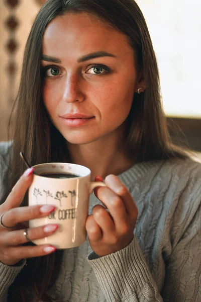 Close up portret pięknej młodej kobiety pijącej filiżankę kawy przy oknie w domu — Zdjęcie stockowe