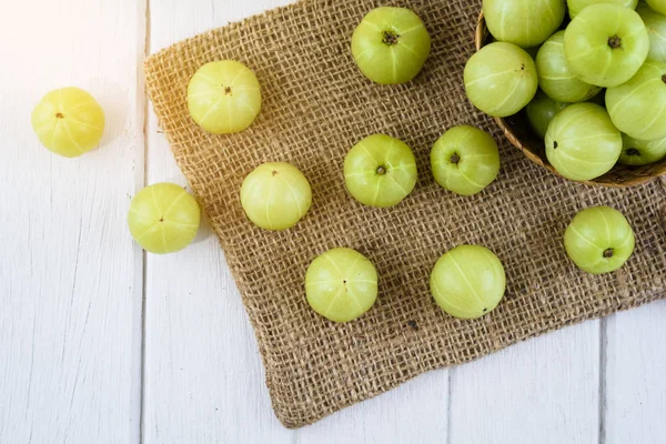 Hasır sepet ve suyu, Beyaz ahşap masa üstünde çul Hint bektaşi üzümü