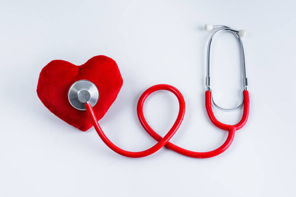 Red heart and stethoscope on white table with copy space