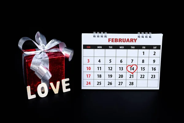 Calendar with red written heart highlight on February 14 of Saint Valentines day with gift box Wooden letters word \