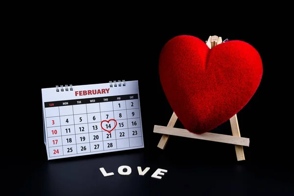 Calendar with red written heart highlight on February 14 of Saint Valentines day with heart shape Wooden letters word \