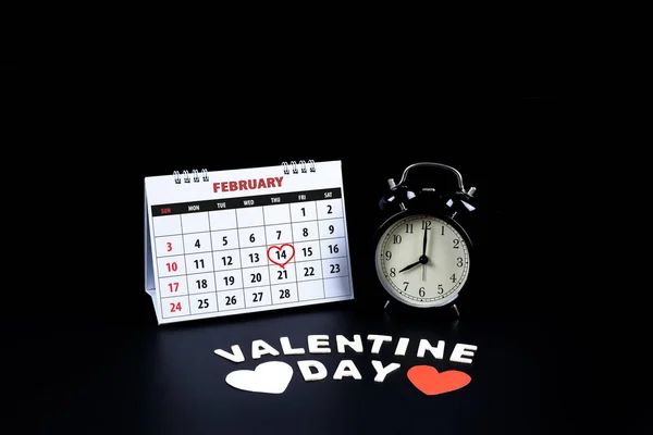 Calendar with red written heart highlight on February 14 with heart shape and alarm clock, gift box, Wooden letters word \