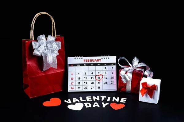 Calendar with red written heart highlight on February 14 with heart shape and gift box, Wooden letters word 