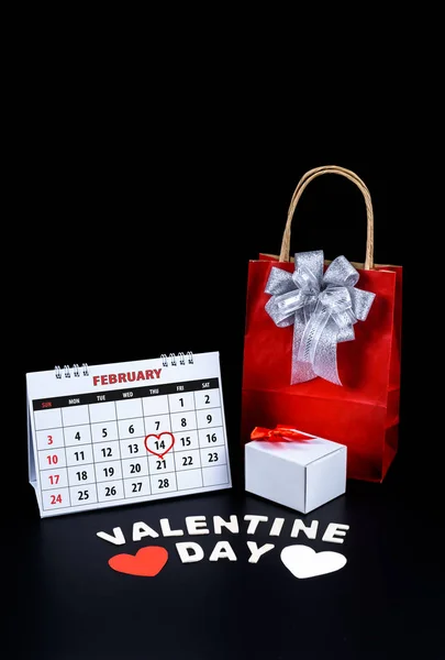 Calendar with red written heart highlight on February 14 with heart shape and gift box, Wooden letters word 