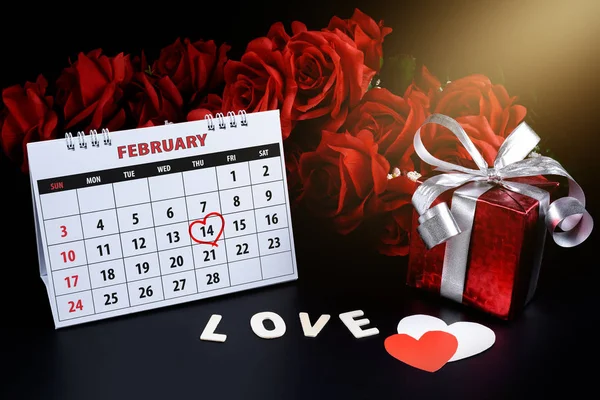 Calendar with red written heart highlight on February 14 with heart shape and gift box, Wooden letters word \