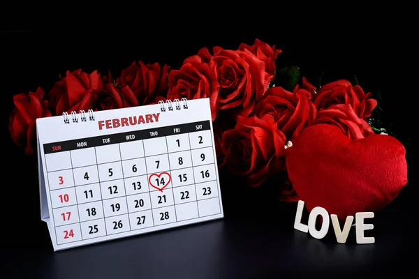 Calendar with red written heart highlight on February 14 with heart shape and Wooden letters word \