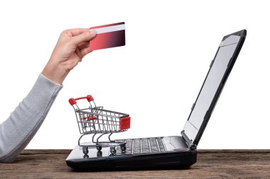 Küçük alışveriş sepeti ve kredi kartı izole kırpma yolu ile beyaz arka plan ile bir el ile dizüstü bilgisayar. Online alışveriş kavramları