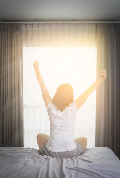 Asian Woman stretching in bed after wake up, back view