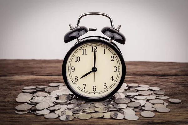 木製のテーブル 保存概念の時間に黒の目覚まし時計とコインのスタック — ストック写真