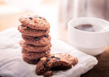 Çikolatalı kurabiye peçete ve ahşap masa üzerinde sıcak çay. Yığılmış çikolatalı kurabiye yakın çekim