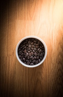 kavrulmuş kahve çekirdekleri ahşap arka plan üzerinde beyaz Kupası arka plan olarak kullanılabilir
