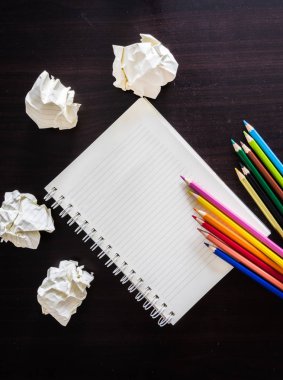 renkli kalemler ve ahşap doku üstünde defter. Resim, çizim ve çizim için arka plan.