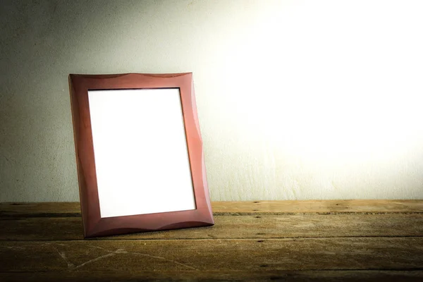 still life of photo frame on wooden table over grunge background. vintage tone