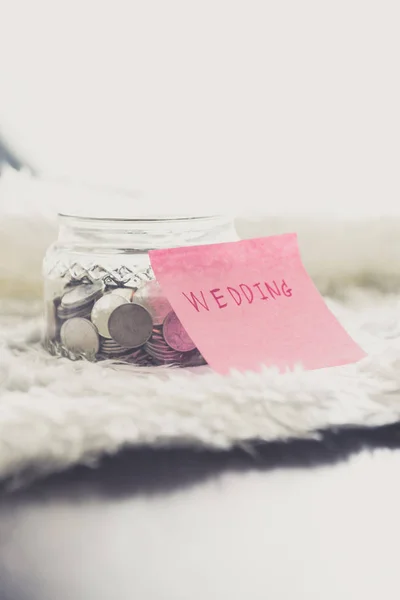 many coins in a money jar with wedding label on jar. wedding concept. saving concept