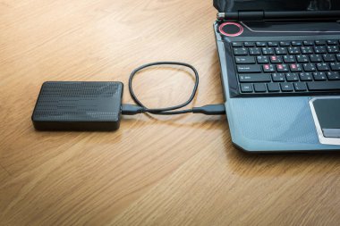 Ahşap arka plan üstünde laptop bağlı harici sabit disk