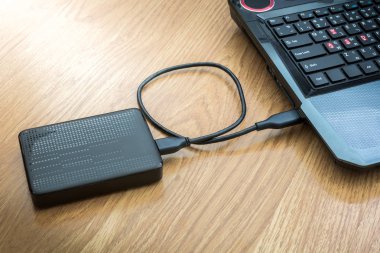 Ahşap arka plan üstünde laptop bağlı harici sabit disk