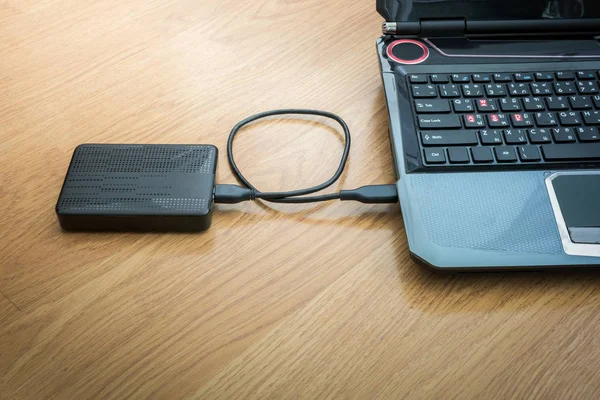 Ahşap arka plan üstünde laptop bağlı harici sabit disk