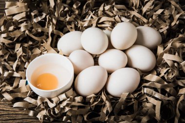 Natürmort ördek yumurta ve saman kağıt ve grunge ahşap arka plan üzerinde bir kasede yumurta sarısı