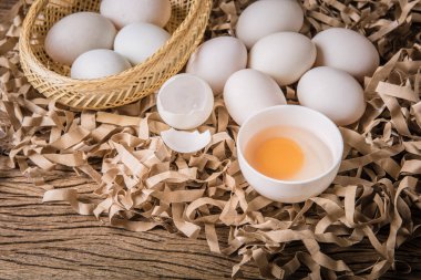 Natürmort ördek yumurta ve saman kağıt ve grunge ahşap arka plan üzerinde bir kasede yumurta sarısı