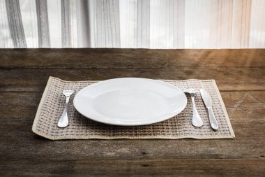 kaşık, çatal, bıçak ve Platemat ahşap arka plan üzerinde beyaz tabak. Retro tarzı renk