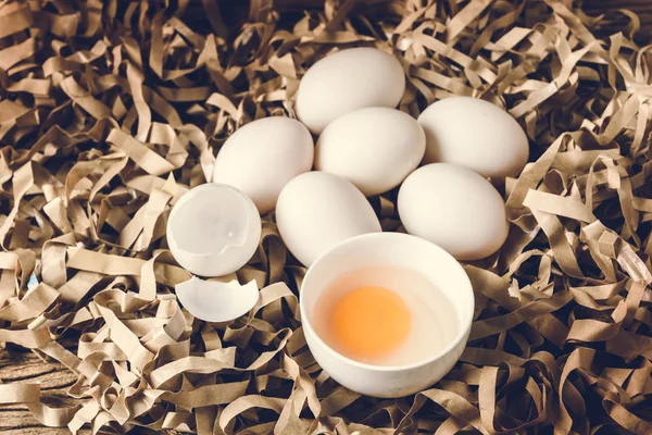 Natürmort ördek yumurta ve saman kağıt ve grunge ahşap arka plan üzerinde bir kasede yumurta sarısı