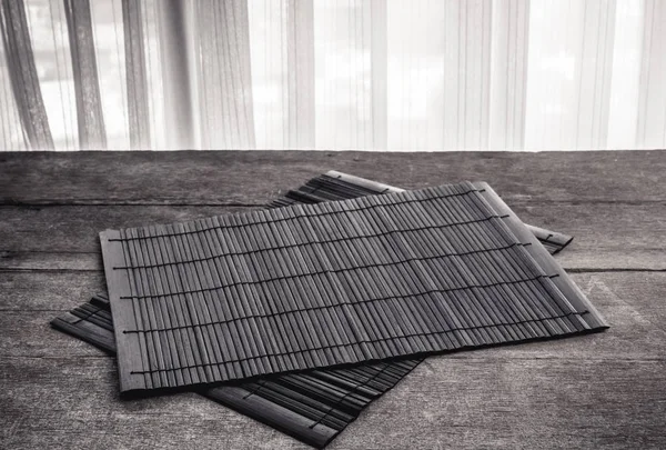 Coaster, koyu kahverengi bambu hasır ahşap arka plan üzerinde. Siyah ve beyaz renk tonu