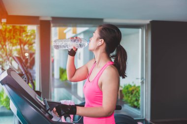 İçme suyu moonwalker fitness makineleri tarafından çalışan jimnastik salonu kadın. Asyalı kadın fitness modeli içinde fitness Center'da.