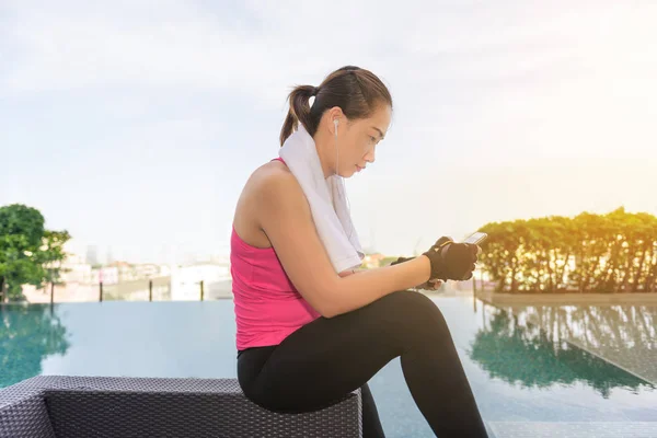 Active girl, fitness girl using smartphone in fitness Beside swimming pool After Exercise in Gym