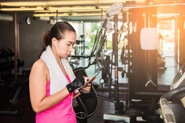 Active girl, fitness girl using smartphone in fitness gym