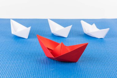 Beyaz ve mavi arka plan arasında önde gelen kırmızı kağıt gemi ile liderlik kavramı