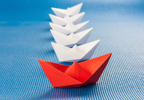 Leadership concept with red paper ship leading among white and blue background