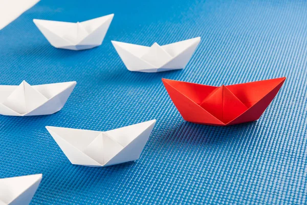 Leadership concept with red paper ship leading among white and blue background