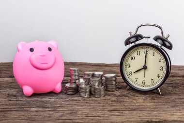 Madeni para yığınları ve çalar saat ile Piggy banka