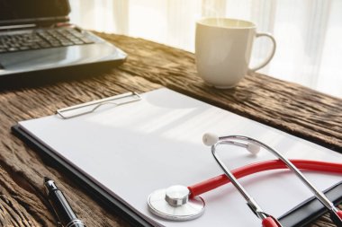 Doktor çalışma alanı stetoskop ve panosu ahşap masa ile