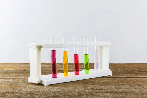 Veelkleurige reageerbuizen in de stand op houten tafel — Stockfoto